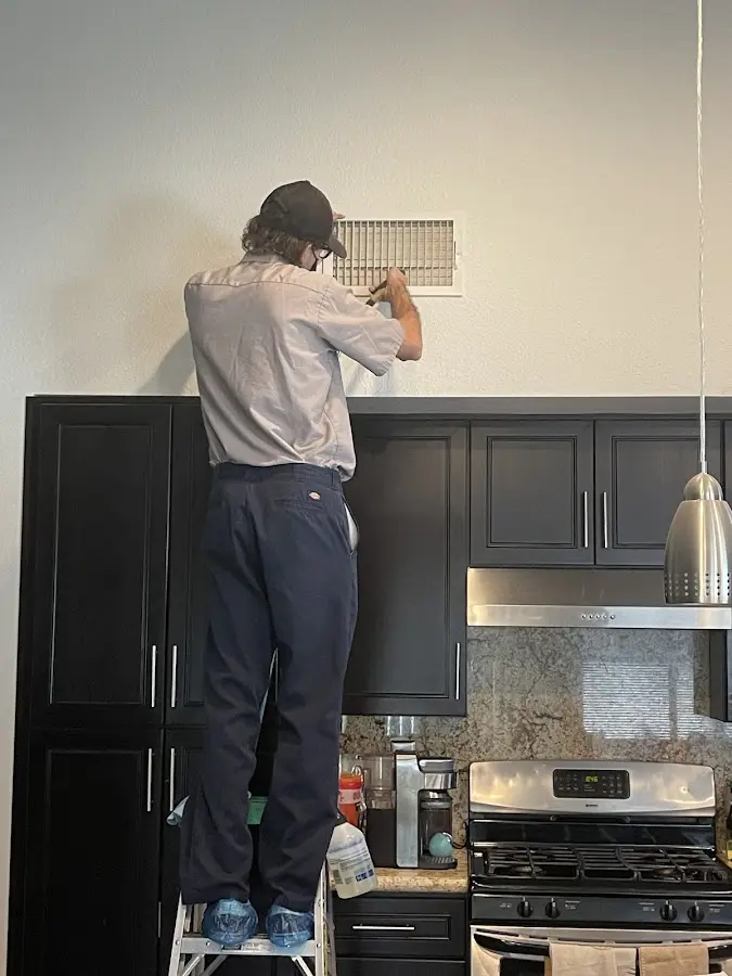 Technician inspecting an air vent during HVAC service in San Carlos